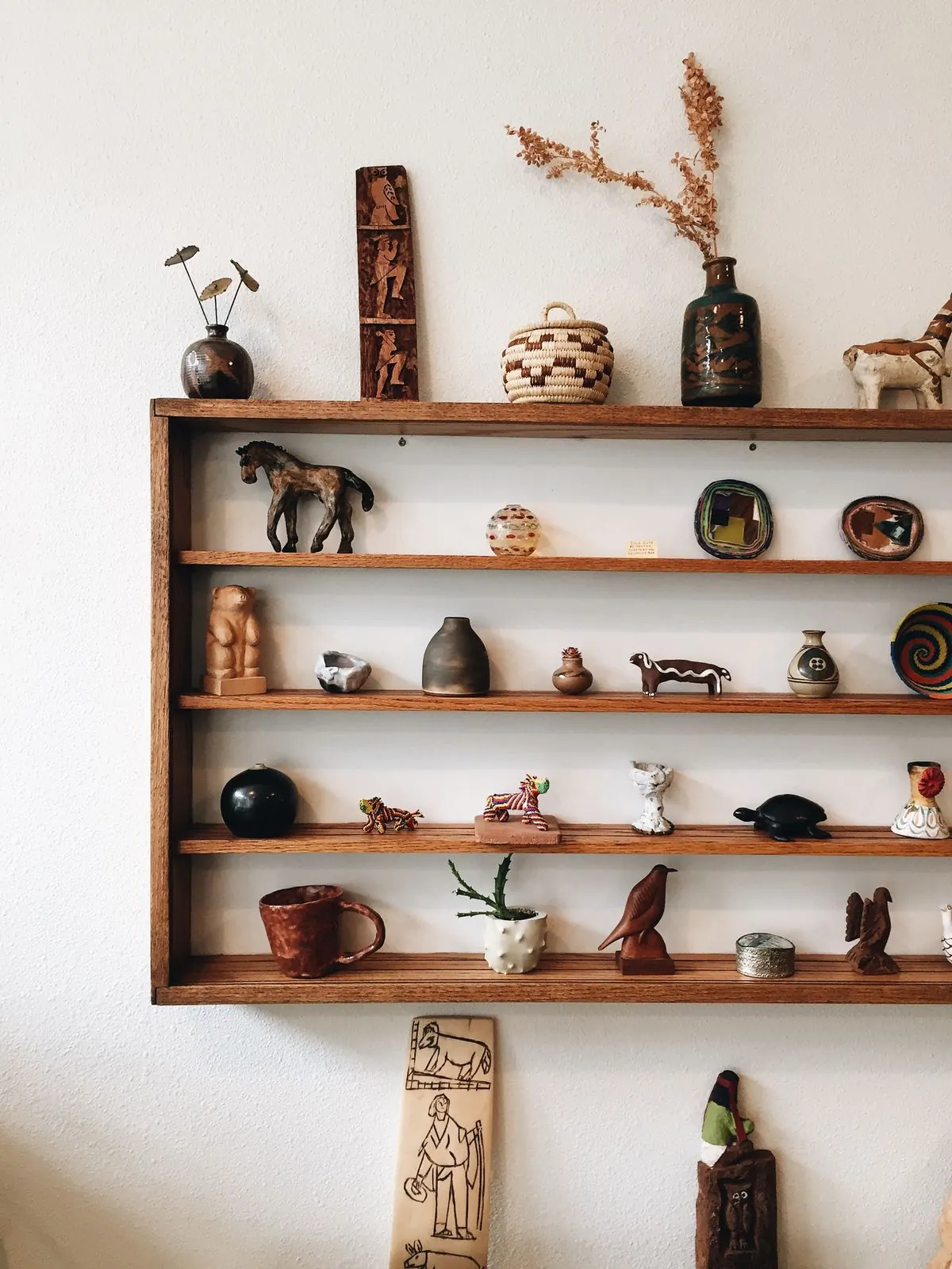 Étagère murale en bois présentant quelques objets chinés espacés : vases, figurines et petite vannerie
