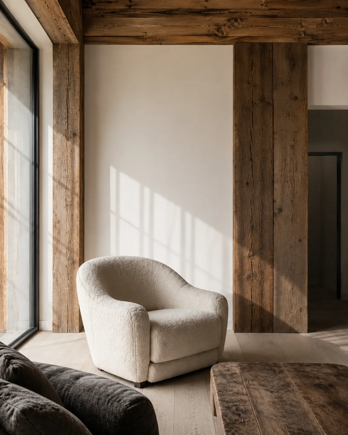 Salon avant relooking : mur blanc nu, fauteuil bouclette et poutres en bois brut, pièce encore vide